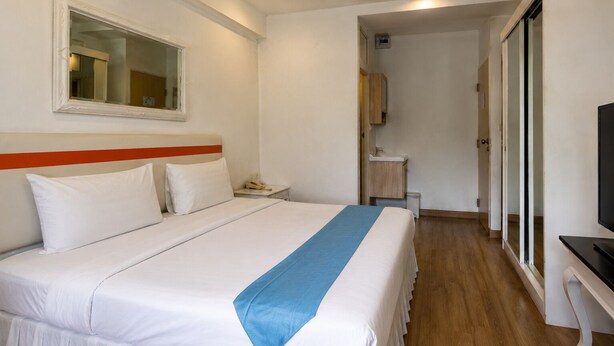 A hotel room with a bed, a TV, a bathroom, and a mirror. - Suk41 (Bangkok)