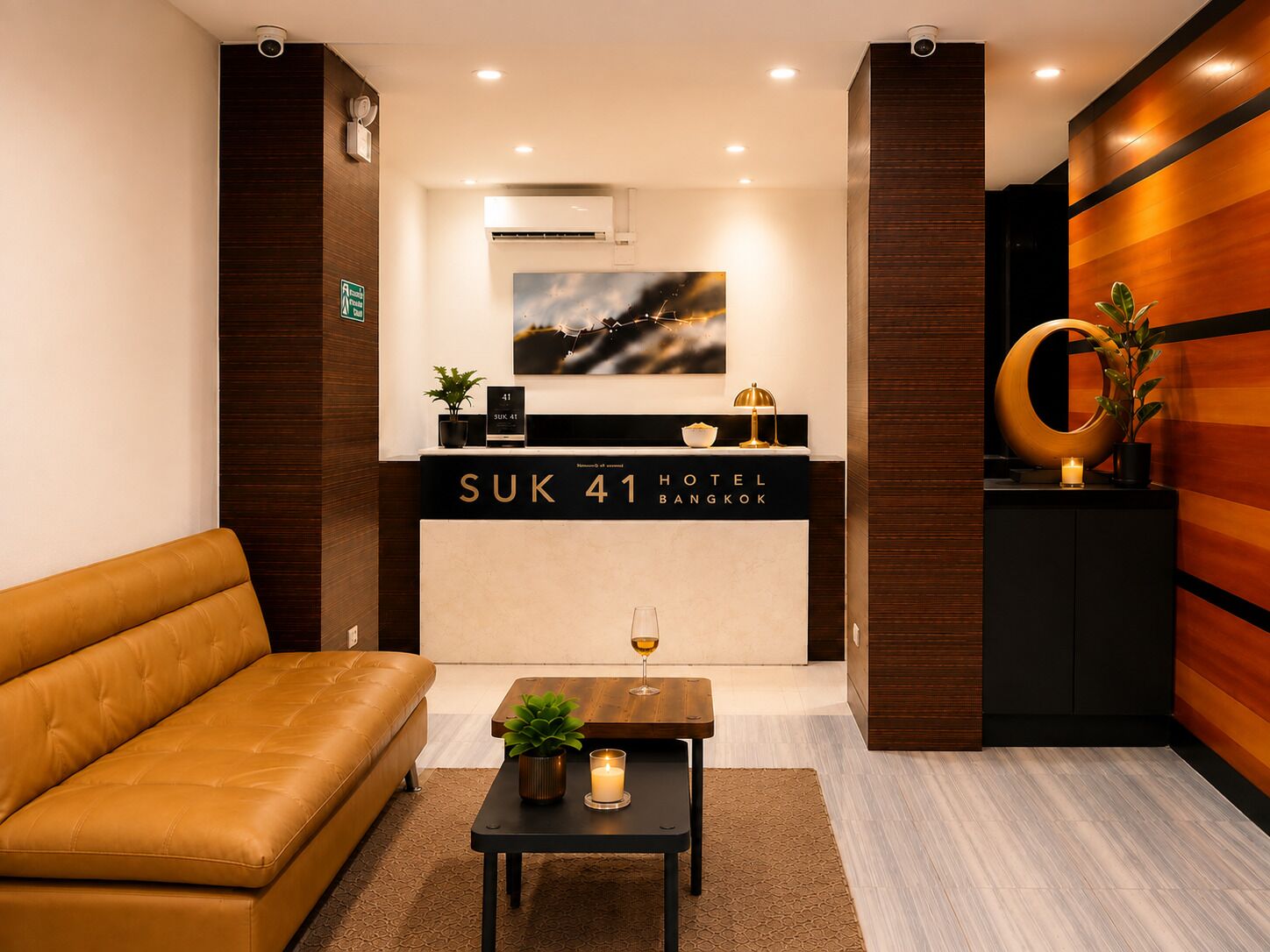 A hotel reception area with a sofa, a reception desk, a framed picture, and a potted plant.