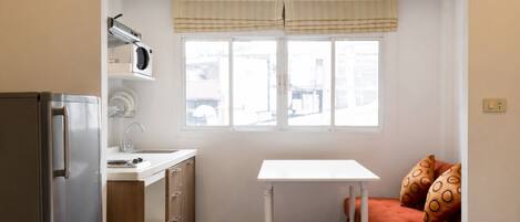 Cocina pequeña con refrigerador, lavamanos y ventana.