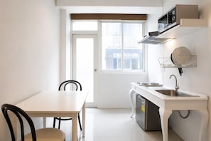 Cocina compacta con encimera blanca, lavavajillas integrado y ventana con vistas a un balcón.