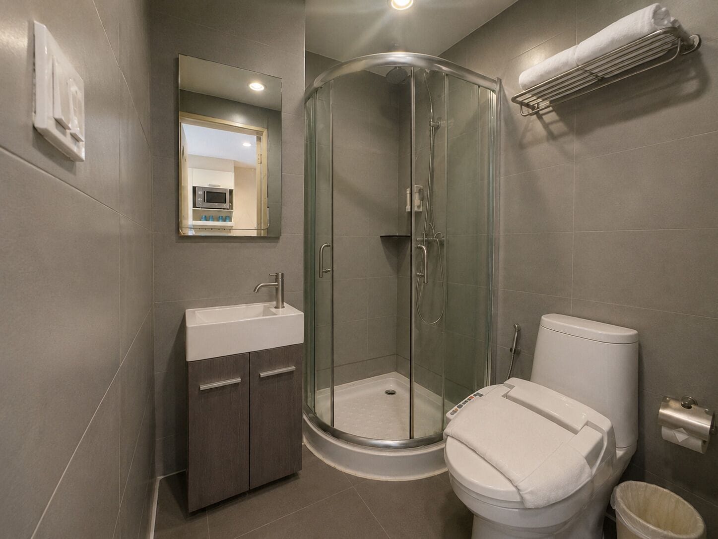 Une salle de bain moderne avec une douche à parois de verre, un lavabo blanc et des toilettes.