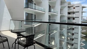 A modern building with multiple balconies, glass railings, and a clear sky.