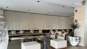 A modern lounge area with sofas, ottomans, and a coffee table.