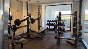 A gym with weightlifting equipment, benches, and dumbbells.