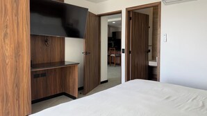 A bedroom with a bed, wooden wardrobe, and a TV.
