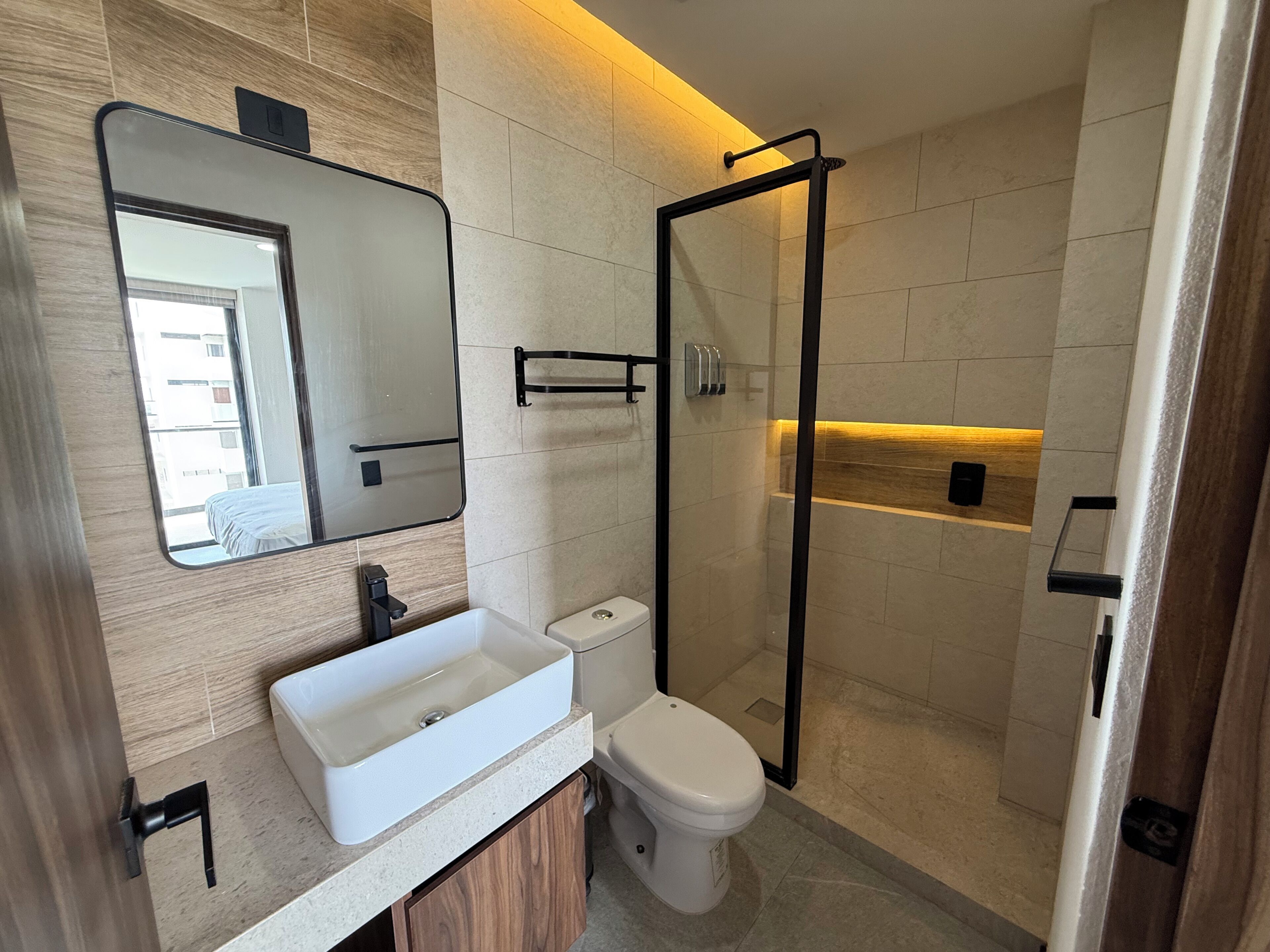 Un baño moderno con lavamanos, inodoro y cabina de ducha de vidrio.