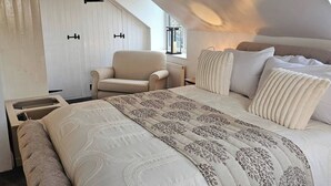 Een slaapkamer met een groot bed, een stoel, een raam en een radiator.