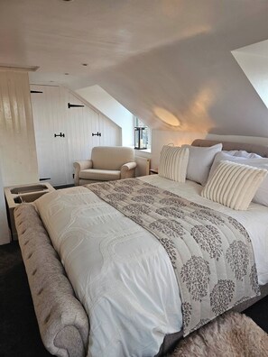 A bedroom with a large bed, a chair, a window, and a radiator. - A Romantic Retreat in a Stunning Setting (Newark)