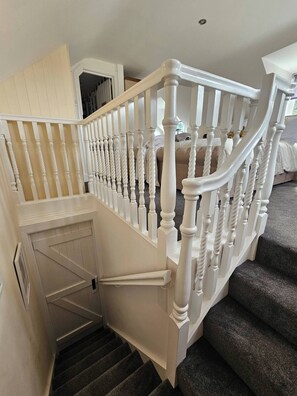 A staircase with white balusters and a handrail, leading to a landing with a door. - A Romantic Retreat in a Stunning Setting (Newark)