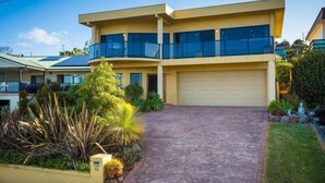 A modern two-story house with a garage, surrounded by a landscaped garden. - Kyeema (Bega Valley)