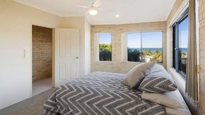 A bedroom with a bed, a ceiling fan, a window, and a view of the outdoors. - Kyeema (Bega Valley)