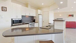 A modern kitchen with white cabinets, a granite countertop, and stainless steel appliances. - Kyeema (Bega Valley)