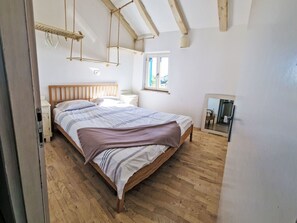 A bedroom with a wooden bed, a bedside table, a hanging light fixture, and a window with a view.