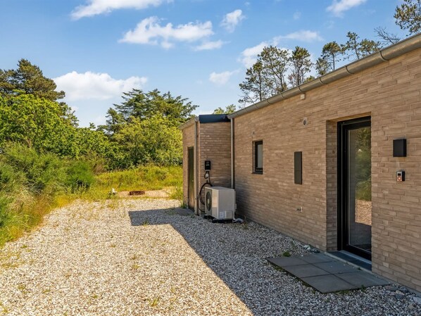 Un bâtiment moderne avec une allée en gravier, un petit climatiseur et une porte.