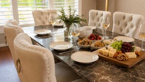 Uma mesa de jantar posta com pratos, copos e uma variedade de alimentos, incluindo queijo, nozes e uvas.