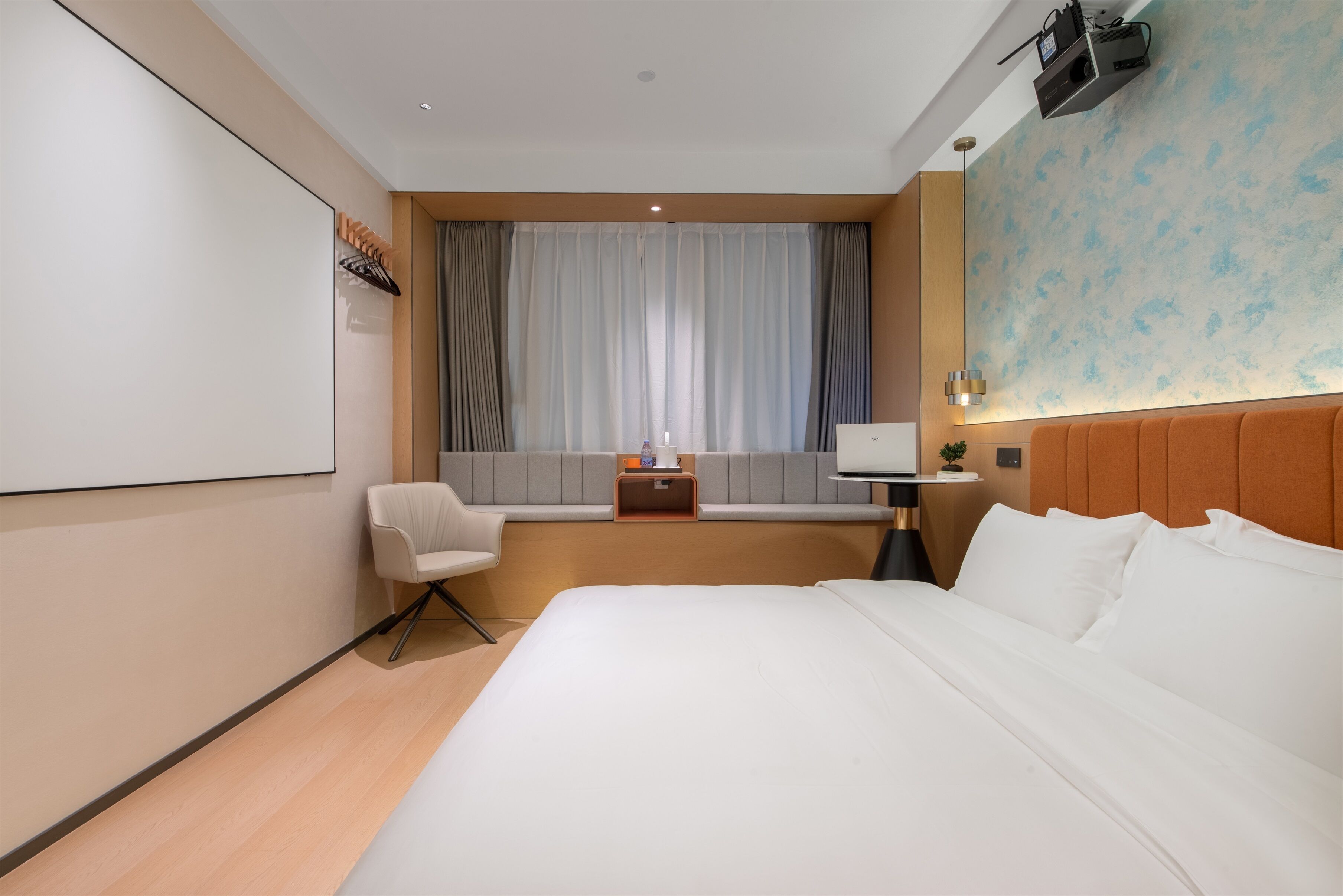 A modern hotel room with a large bed, a seating area with a chair, a small table, and a television.