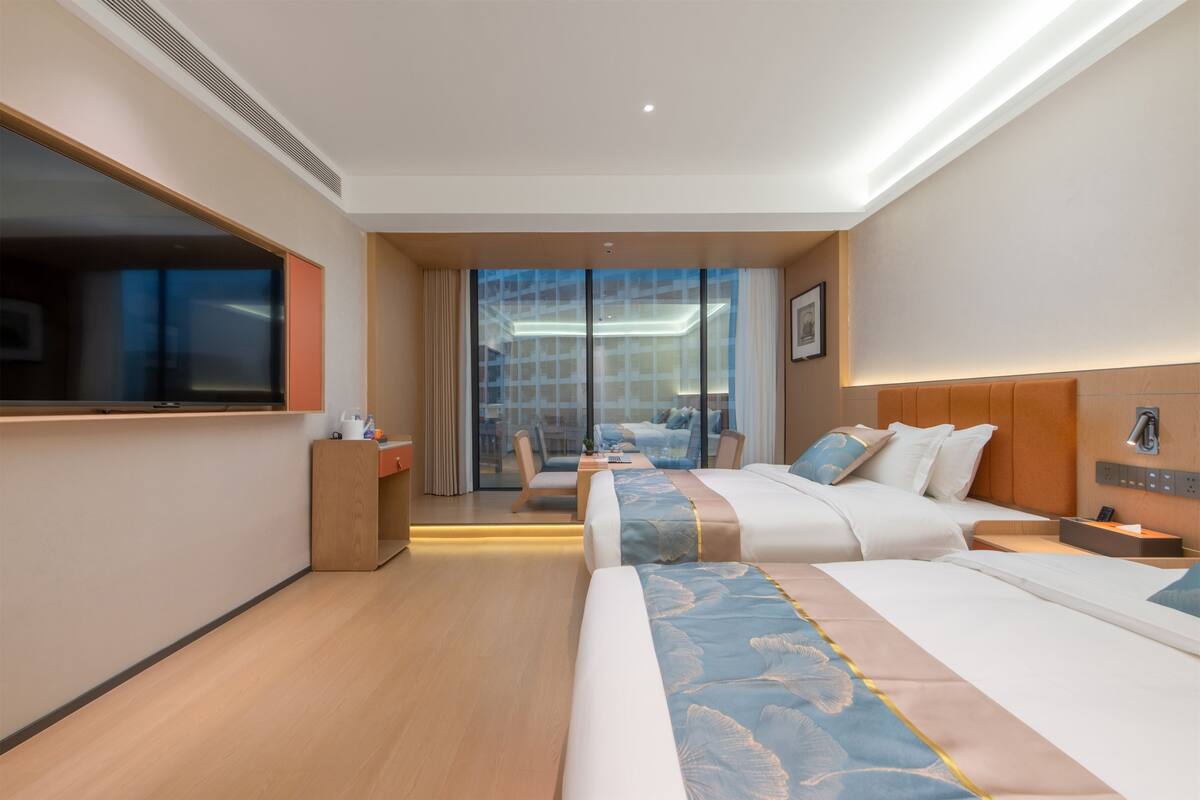 Ein Hotelzimmer mit einem großen Bett, einem Schreibtisch, einem Sessel und einem Fernseher.