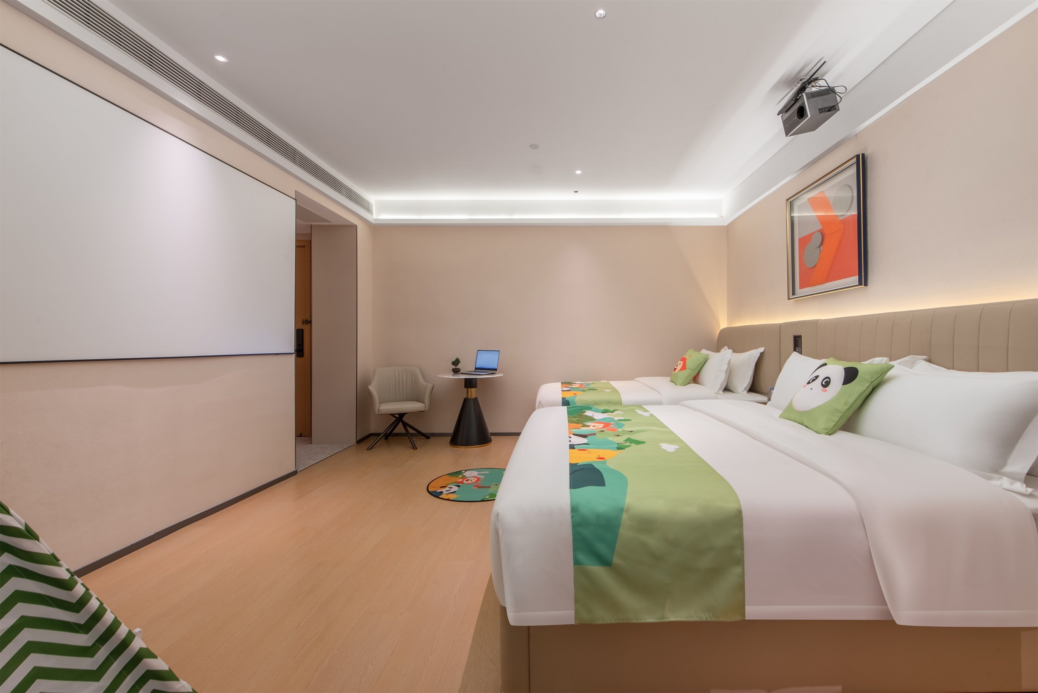 Habitación de hotel con cama, escritorio, silla y proyector montado en la pared.