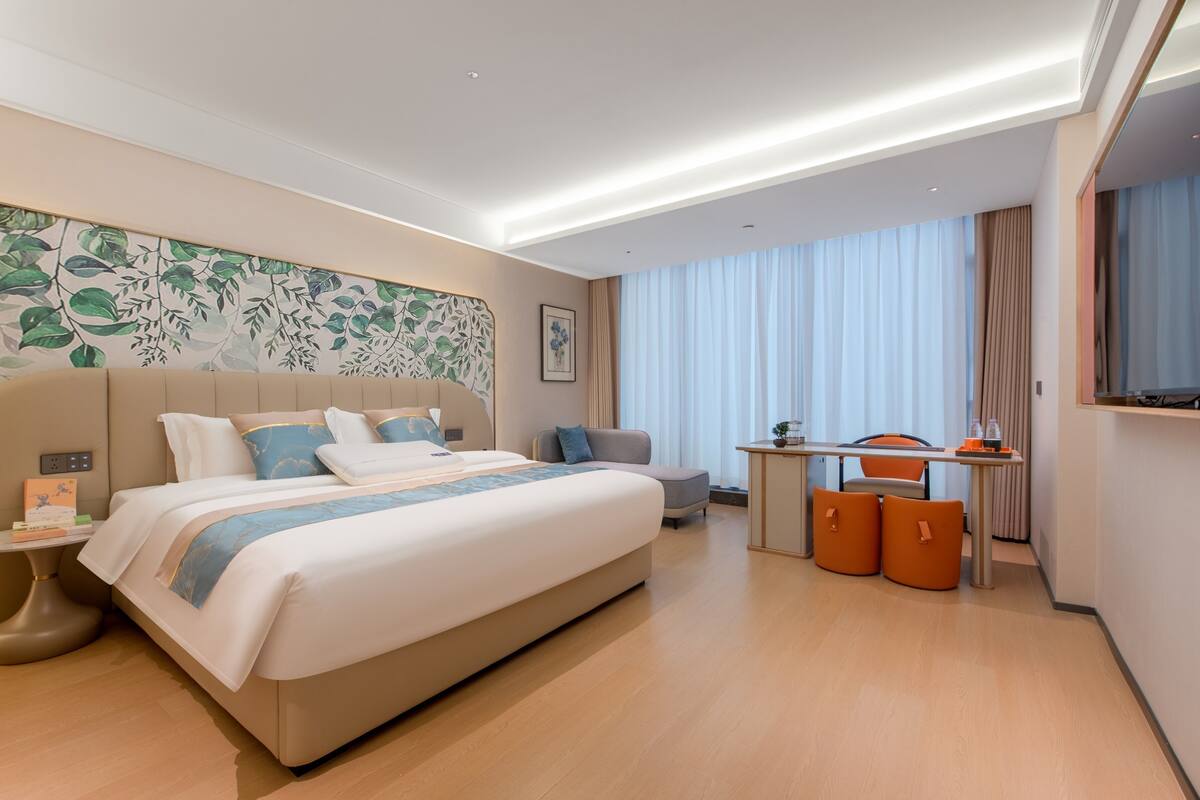 Ein modernes Hotelzimmer mit einem großen Bett, einem Schreibtisch und einem Fernseher.