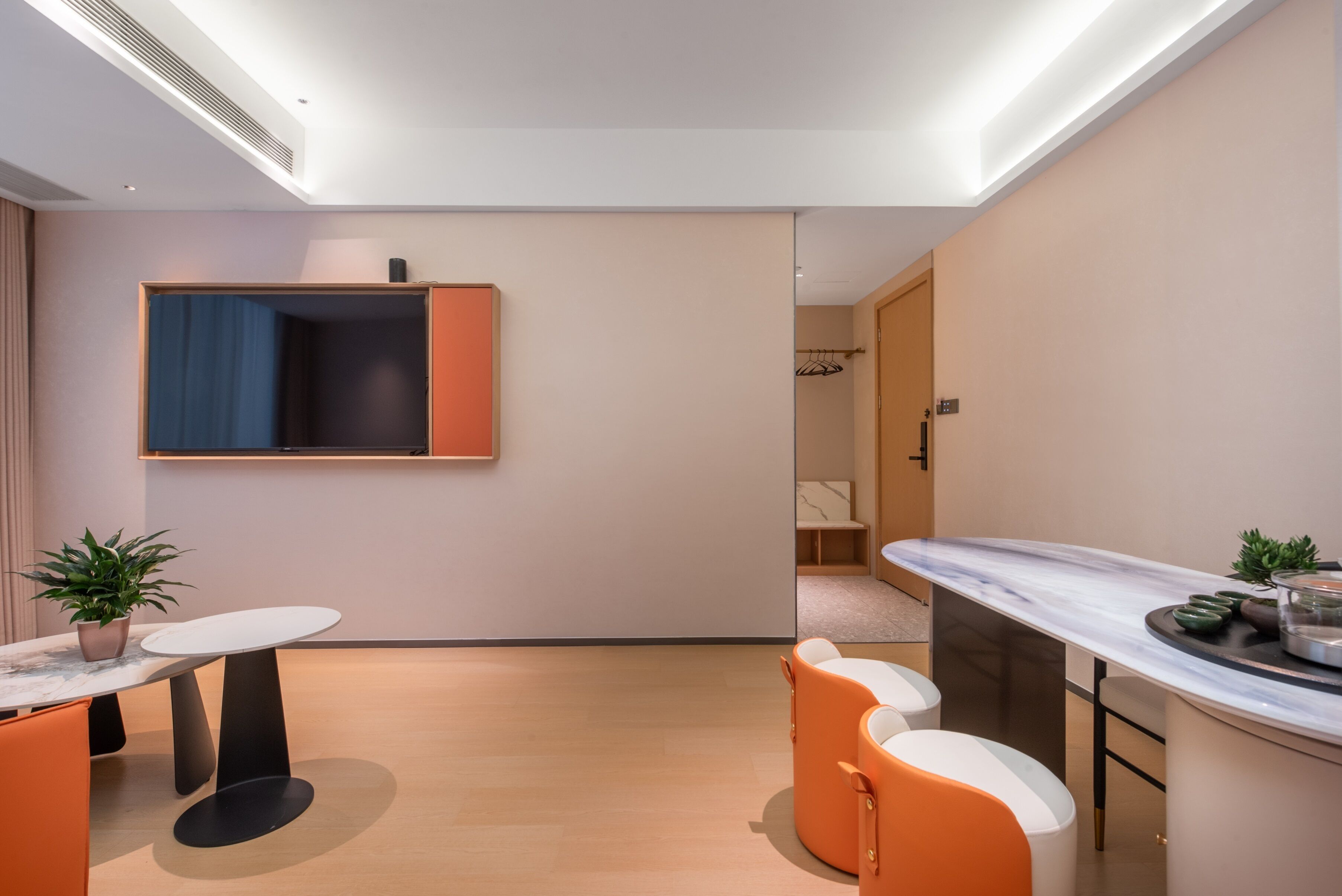 A modern room with a dining table, chairs, a small kitchen area, and a wardrobe.