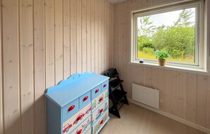 A room with wooden walls, a window with a view of greenery, a blue storage unit with drawers, and a black chair. - Pet friendly home in Tarm with sauna (Tarm)