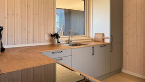 Une cuisine de taille réduite, dotée d’un plan de travail en bois, d’un évier et d’une fenêtre.