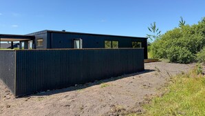 Un bâtiment moderne à l’extérieur sombre, doté de grandes fenêtres et d’un toit plat.