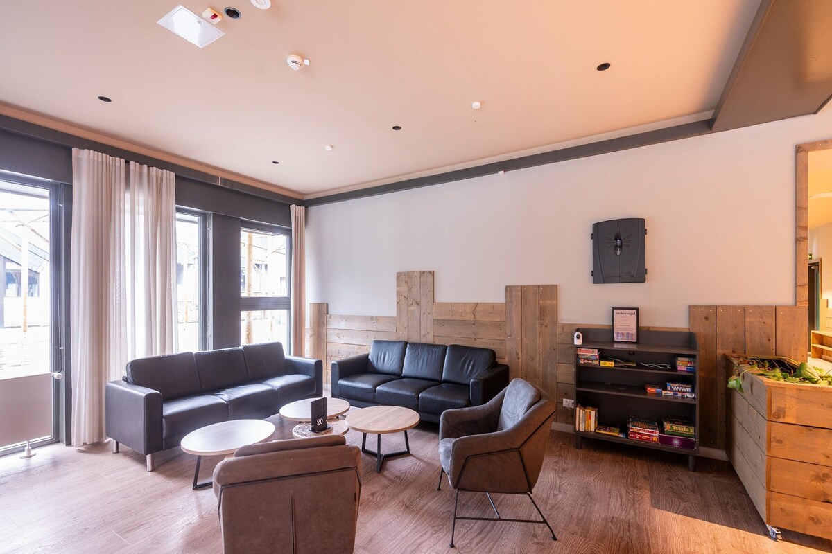 Ein modernes Wohnzimmer mit einer Couch, Sesseln, einem Couchtisch und einem Bücherregal.