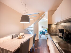 Eine moderne Küche mit Essbereich, einer Treppe und einem sichtbaren Wohnzimmer im Hintergrund.