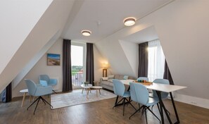Ein modernes Zimmer mit Esstisch, Stühlen, einer Couch und einer Lampe.