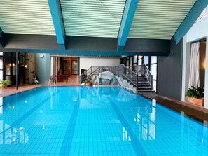 An indoor swimming pool with a tiled floor, a staircase with a railing, and a view of the interior. - Hambachtal Forest Hideaway Boutique Resort (Oberhambach)