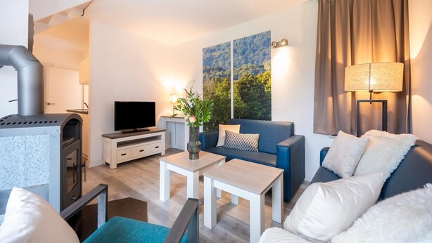 Una sala de estar moderna con chimenea, televisor de pantalla plana, sofá, mesa de centro y lámpara.