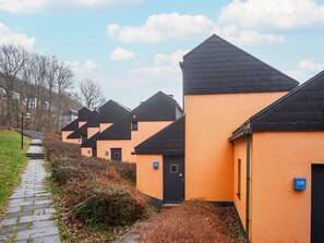 A row of orange buildings with black roofs, numbered signs, and a paved pathway. - Hambachtal Forest Hideaway Boutique Resort (Oberhambach)