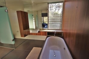 Un bagno moderno con una vasca, uno specchio grande e una finestra.