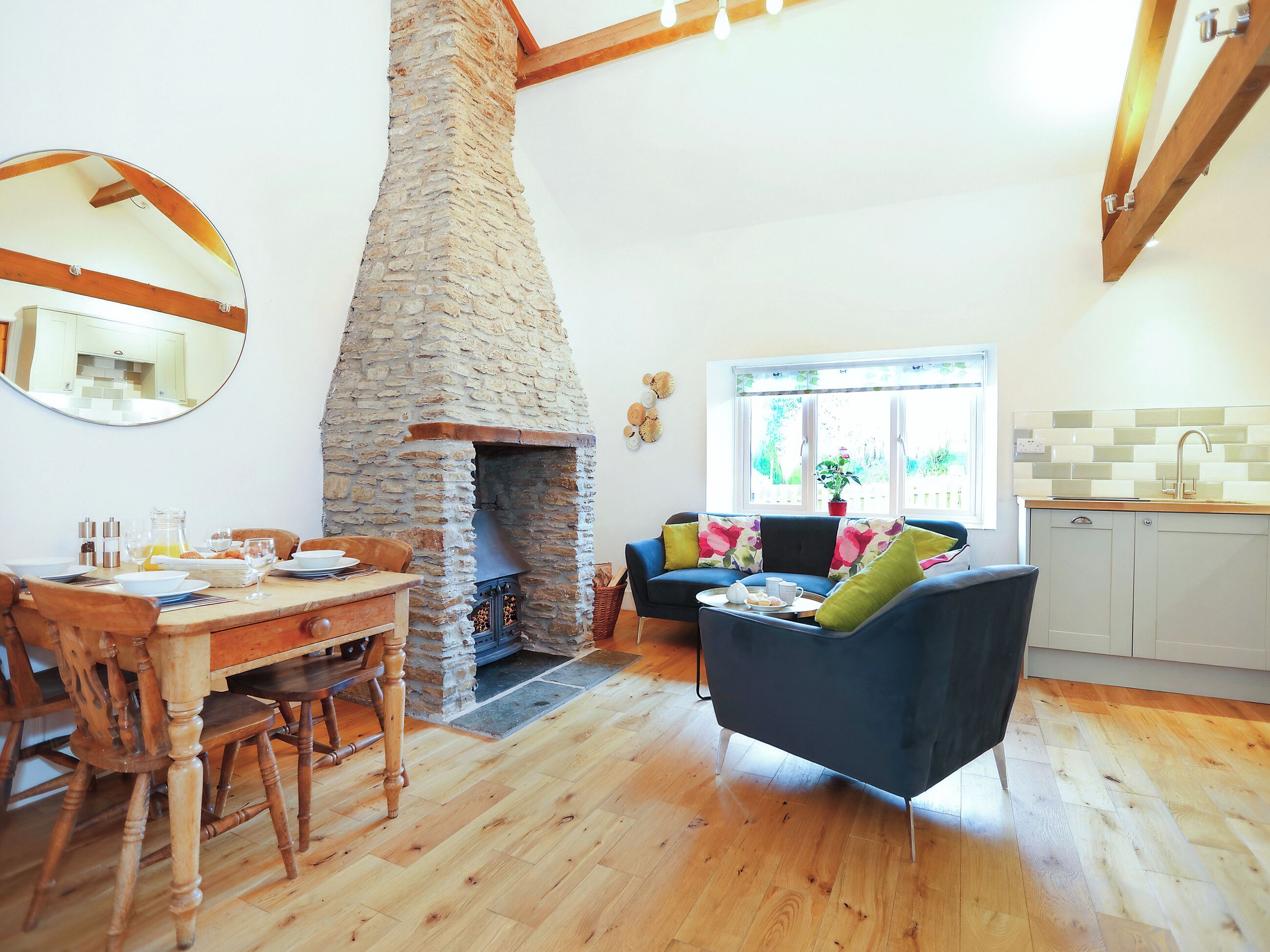 Un salon chaleureux avec une cheminée en pierre, des meubles en bois et une vue sur l’extérieur.