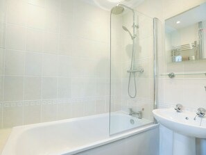 Une salle de bain avec une douche à parois de verre, une baignoire blanche et un lavabo avec un miroir au-dessus.