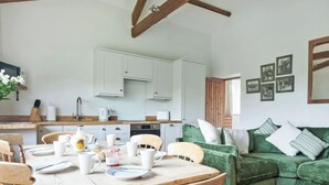 Een gezellige keuken met witte kastjes, een eettafel met stoelen en een groene bank.
