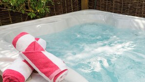 A hot tub with two pink and white towels rolled up inside.