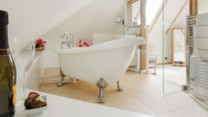 A modern bathroom with a freestanding bathtub, a glass shower enclosure, and a white vanity with a wine bottle and chocolates.