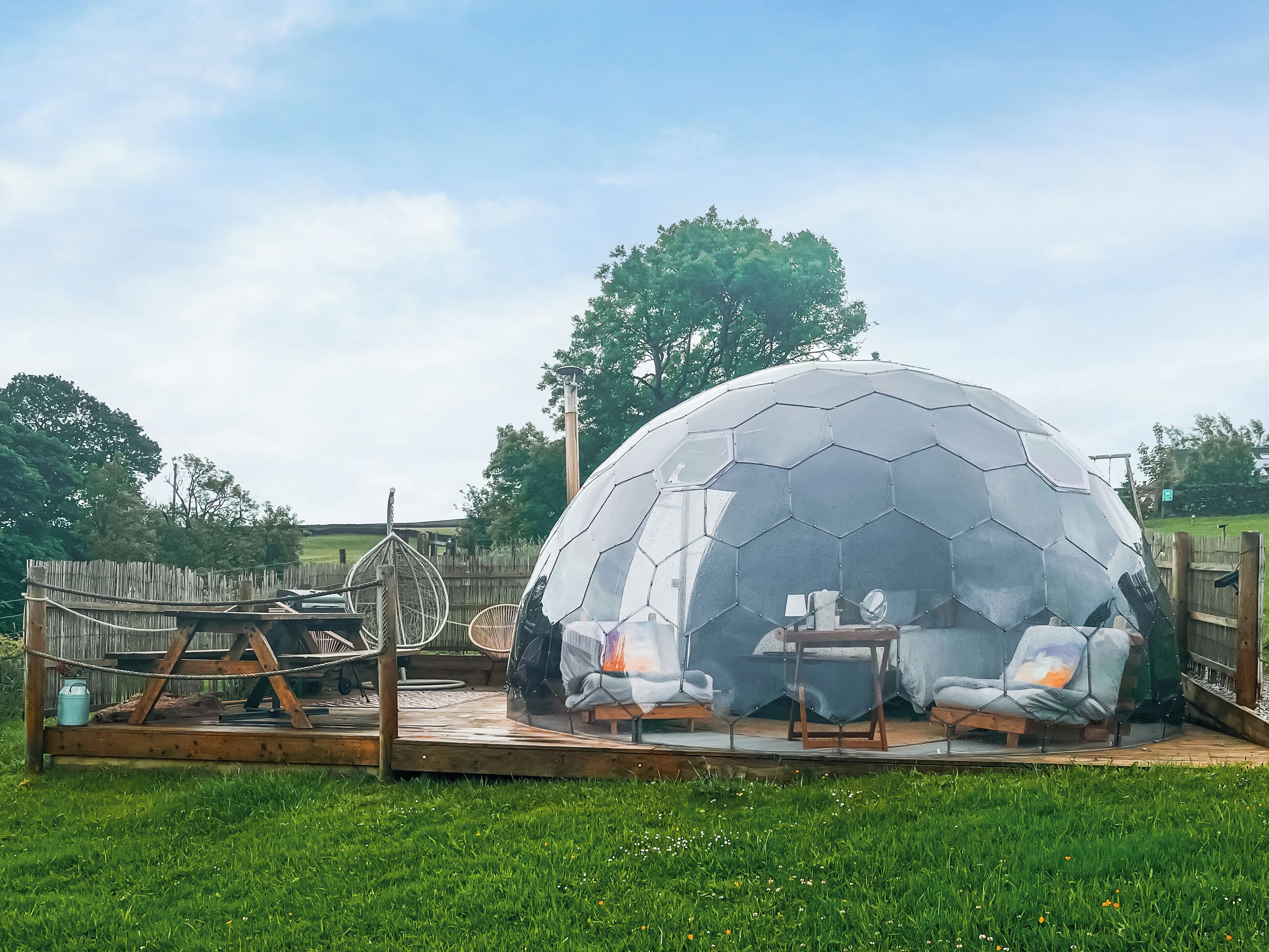 A geodesic dome structure with a wooden deck and seating area.