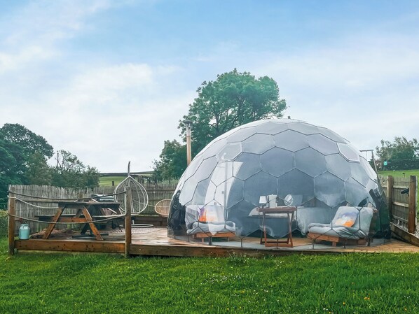 Una estructura geodésica con una terraza de madera y zona de estar.