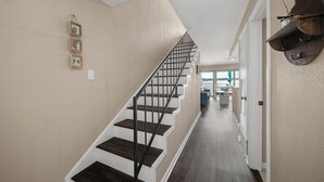 A staircase with a modern design, a hallway leading to a door, and a view of a balcony. - Fishing on the Overwater Balcony! 2BR/2BA Condo with Beautiful Lake Conroe View (Willis)