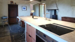Una cocina moderna con una isla grande, horno empotrado y una lámpara colgante.