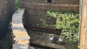 Un edificio de piedra con techo de tejas, un camino empedrado y un ventanal pequeño.