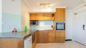 Eine moderne Küche mit Holzschränken, einer Mikrowelle, einem Backofen und einem Geschirrspüler.