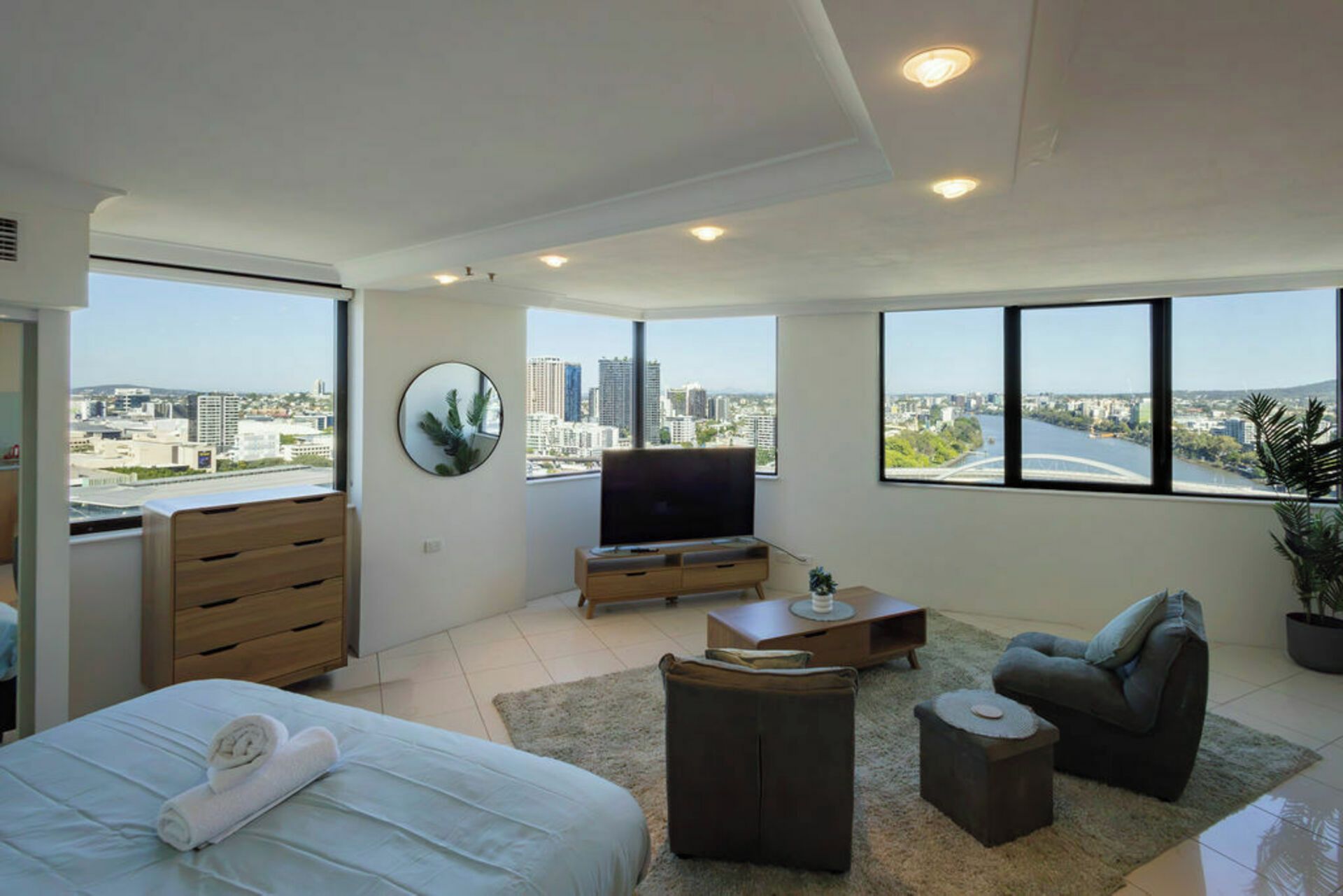 Une chambre moderne avec un lit, une télévision et une vue sur la ville.