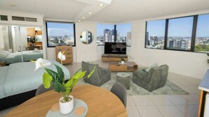 Ein modernes Hotelzimmer mit Blick auf die Stadt, einem Bett, einem Essbereich und einem Fernseher.