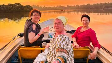 Tres personas en un bote con un atardecer al fondo.