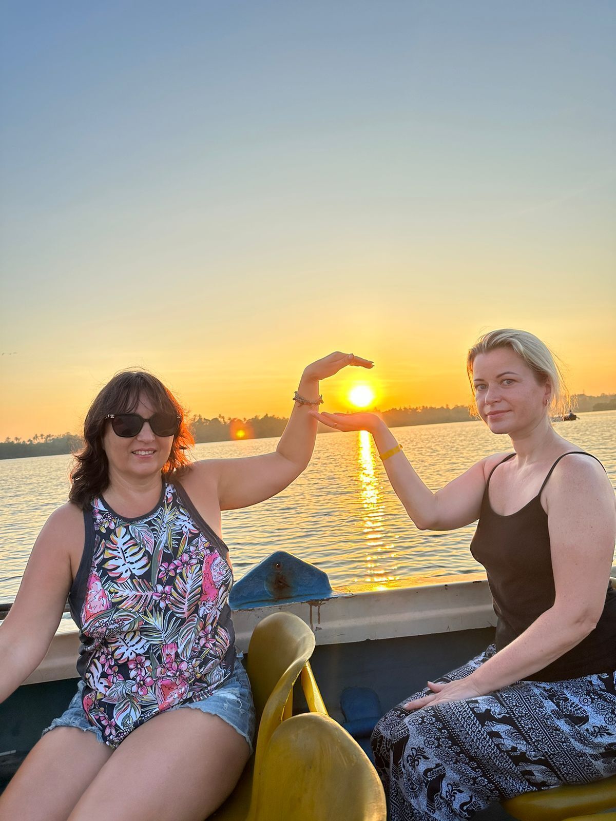 Dos personas en un bote con un atardecer de fondo.