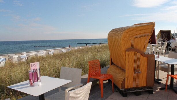 An outdoor seating area with wicker chairs and tables, overlooking a beach with a clear view of the sea. - Fabulous Bungalow in Steffenshagen near Sea (Steffenshagen)